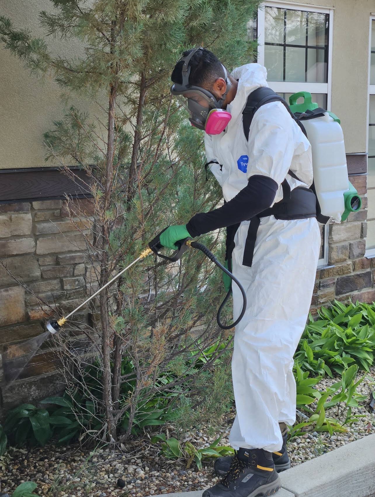 Pest control technician spraying the exterior of a home